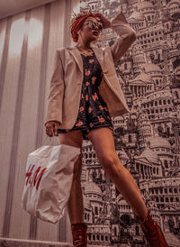 Portrait of young woman standing against wall