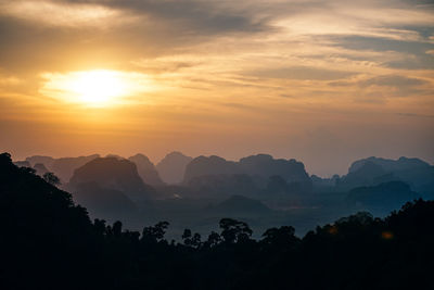 Scenic view of silhouette mountains against orange sky