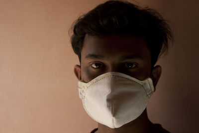 Portrait of young man with mask against wall