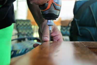 Midsection of carpenter drilling wood