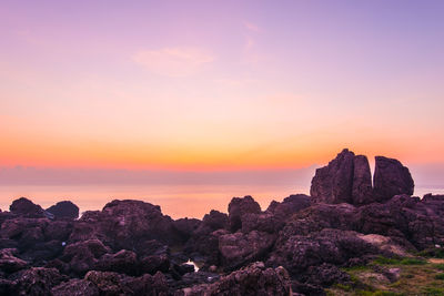 Rock formation on sea against sky during sunset