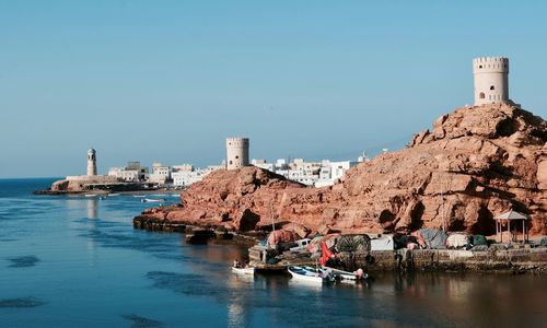 Buildings by sea against clear sky