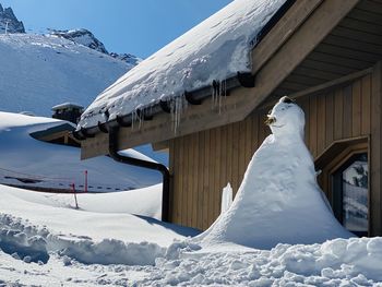 Snow covered houses by snowcapped mountain against sky