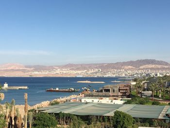 Scenic view of sea and buildings against clear blue sky