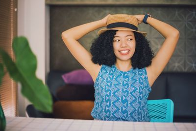 Woman wearing hat looking away while sitting at home