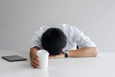 Rear view of man holding coffee cup on table