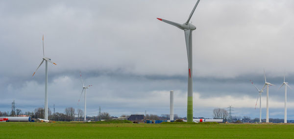 Low angle view of wind turbines on field against sky