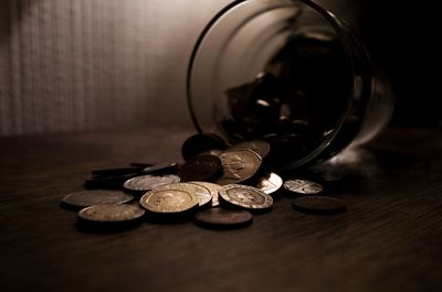 Close-up of coins spilling from jar on table