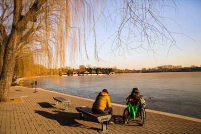 Rear view of people sitting by lake