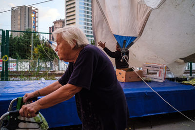 Side view of woman with umbrella standing against buildings