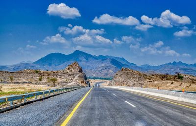 Road leading towards mountains against sky