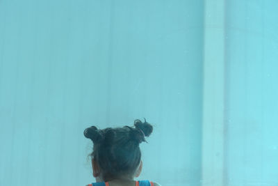 Rear view of woman looking at blue wall