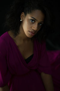 Portrait of young woman against black background