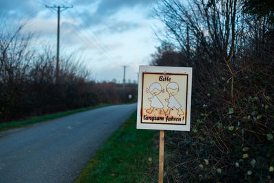 Information sign by road against sky