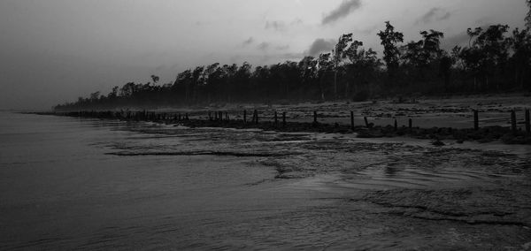 Scenic view of beach against sky at dusk