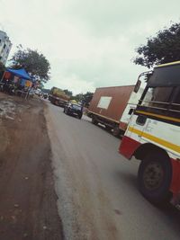 Vehicles on road against sky in city