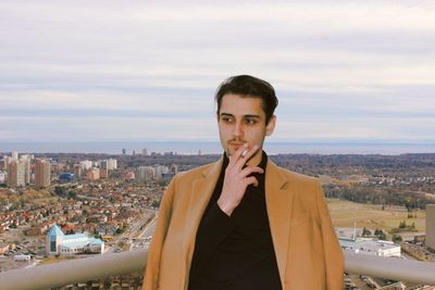 Man smoking cigarette against cityscape