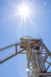 Low angle view of ferris wheel against blue sky on sunny day