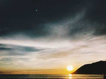 Scenic view of sea against dramatic sky during sunset