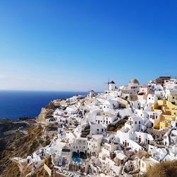 High angle view of town by sea against clear blue sky