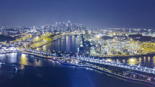 Illuminated bridge over river amidst buildings in city at night