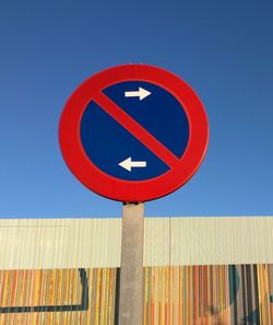 Low angle view of road sign against clear blue sky