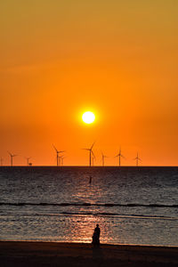 Silhouette people on sea against sky during sunset