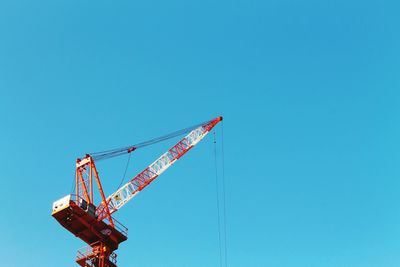 Low angle view of crane against clear blue sky