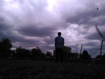 Rear view of silhouette man standing on field against sky