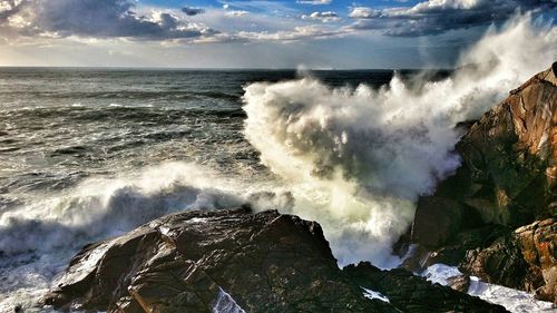 Waves splashing on sea against sky