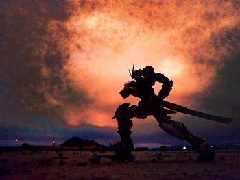 Silhouette man standing on field against sky during sunset