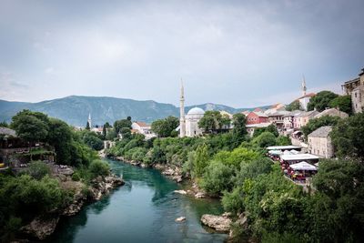 River amidst buildings in city against sky