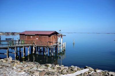 House by sea against clear blue sky