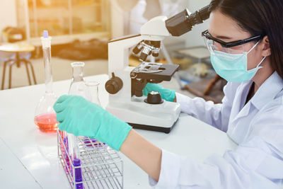 Female scientist using microscope at table in laboratory