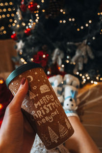 Female hands holding a cup of coffee or tea with a christmas cozy design. winter holiday decor