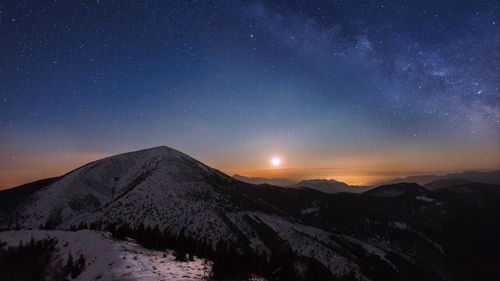 Scenic view of snowcapped mountains against sky at night