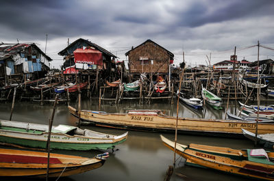 Boats moored at harbor by buildings against sky