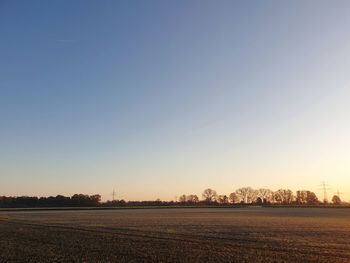 Scenic view of field against clear sky during sunset