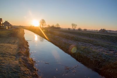 Scenic view of canal against sky during sunset