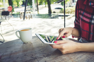Midsection of woman holding coffee cup on table