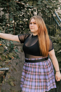 Beautiful young woman standing against plants