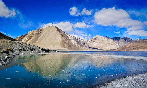 Scenic view of lake and mountains against blue sky