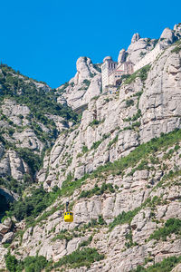 Low angle view of rocky mountain against blue sky