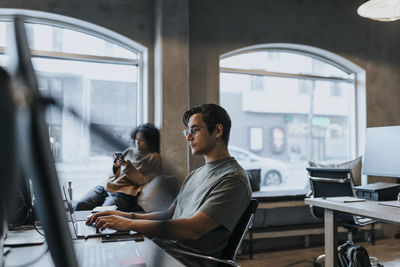 Male computer programmer using laptop while working in startup company