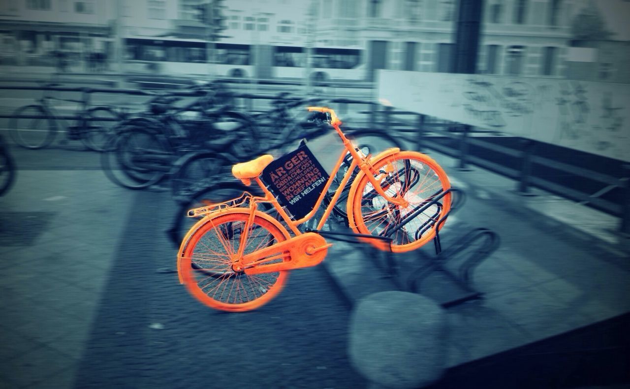 focus on foreground, indoors, bicycle, street, orange color, transportation, close-up, art and craft, no people, creativity, art, yellow, mode of transport, land vehicle, day, animal representation, sidewalk, architecture, built structure