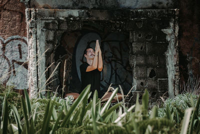Portrait of yoga man by plants in abandoned building