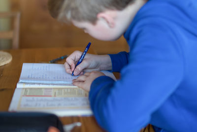 Boy writing on book at table