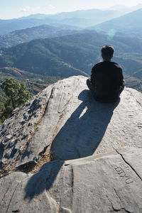 Rear view of man sitting on mountain