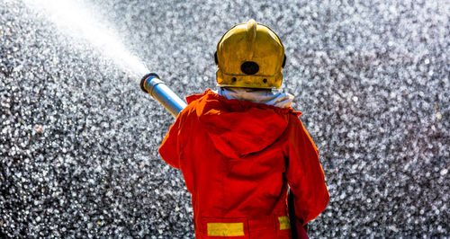 Rear view of firefighter spraying water