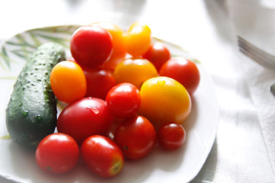 Close-up of tomatoes by cucumber in plate on table